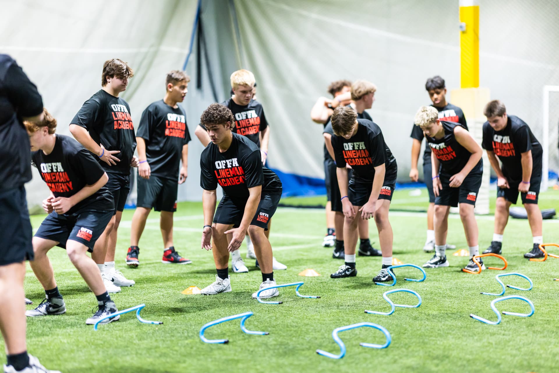 Offa Lineman Academy athletes running conditioning drills on an indoor turf field